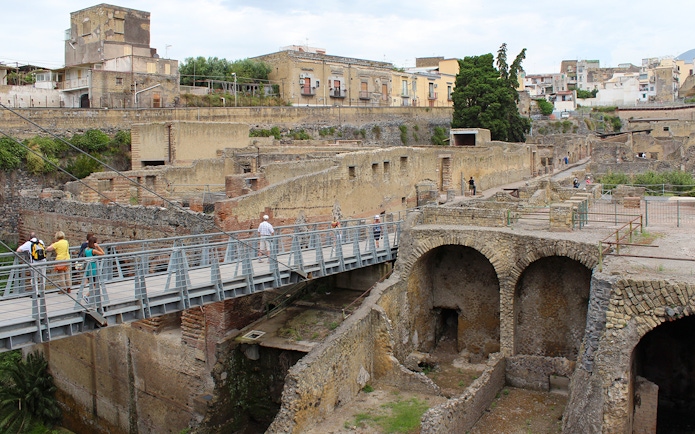 Visitors crossing a bridge towards the ancient ruins of Herculaneum, Italy.
