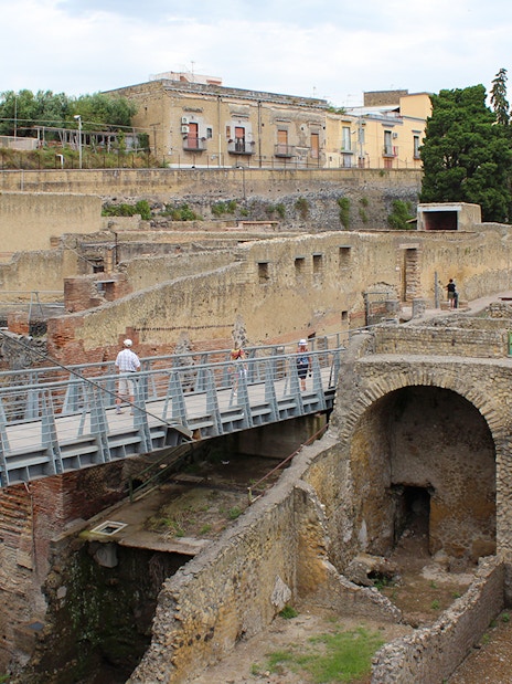 Visitors crossing a bridge towards the ancient ruins of Herculaneum, Italy.