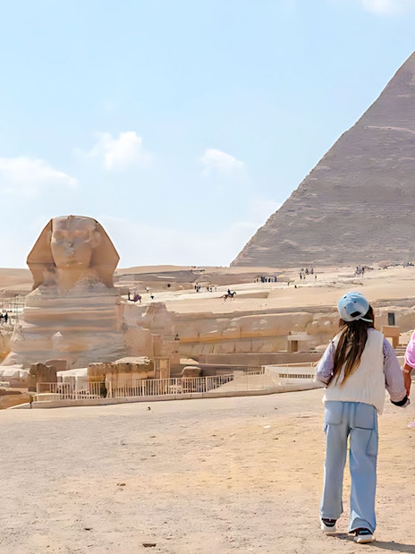 Mother and child walking towards the Pyramid of Giza and Sphinx in Egypt.