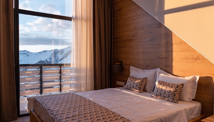 Mountain-view hotel room with large windows and cozy seating area.