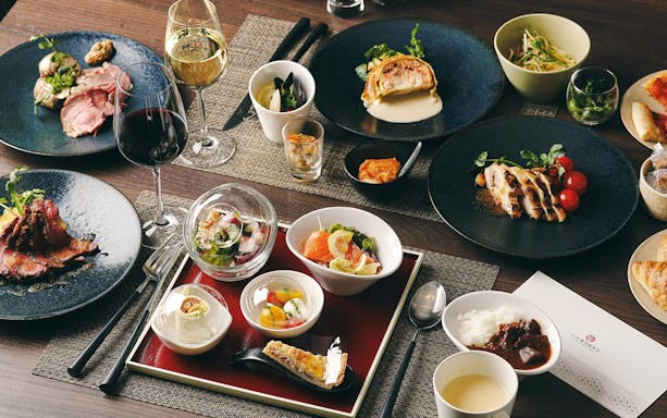 Assorted dishes at Ghibli Museum restaurant, including sushi, salad, and wine.