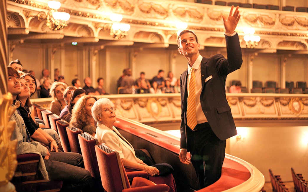 Guide leading a tour group inside the Semper Opera House, Dresden.