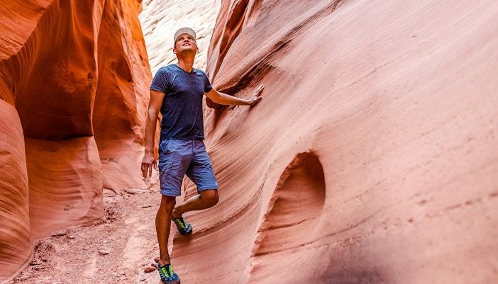 Hiker exploring narrow sandstone walls in Antelope Canyon.