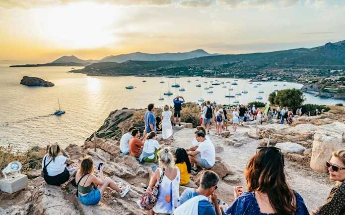 Tourists enjoying sunset views at Cape Sounion near the Temple of Poseidon, Greece.