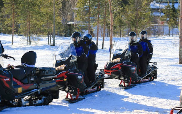 Guests riding snowmobiles on a snowy trail during a safari adventure in Rovaniemi.