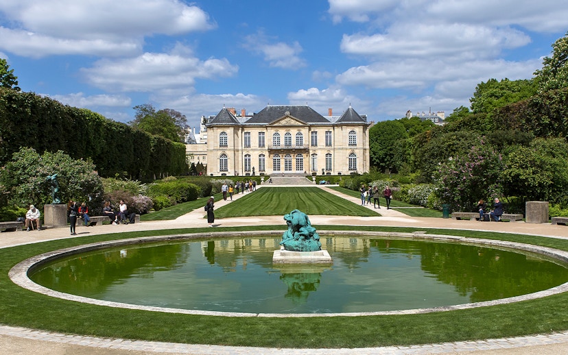 Visitors at the Rodin Museum gardens in Paris, viewing sculptures and the historic building.