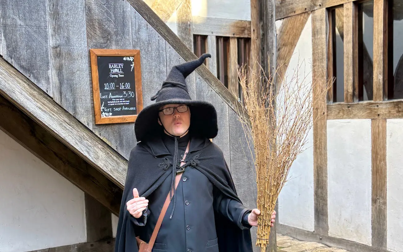 Person in witch costume holding broomstick on York Witches & History Old Town Walking Tour.
