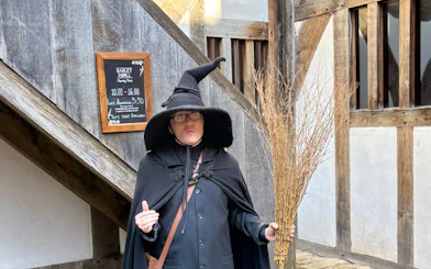 Person in witch costume holding broomstick on York Witches & History Old Town Walking Tour.