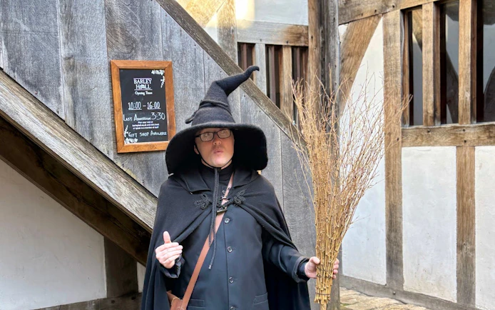 Person in witch costume holding broomstick on York Witches & History Old Town Walking Tour.