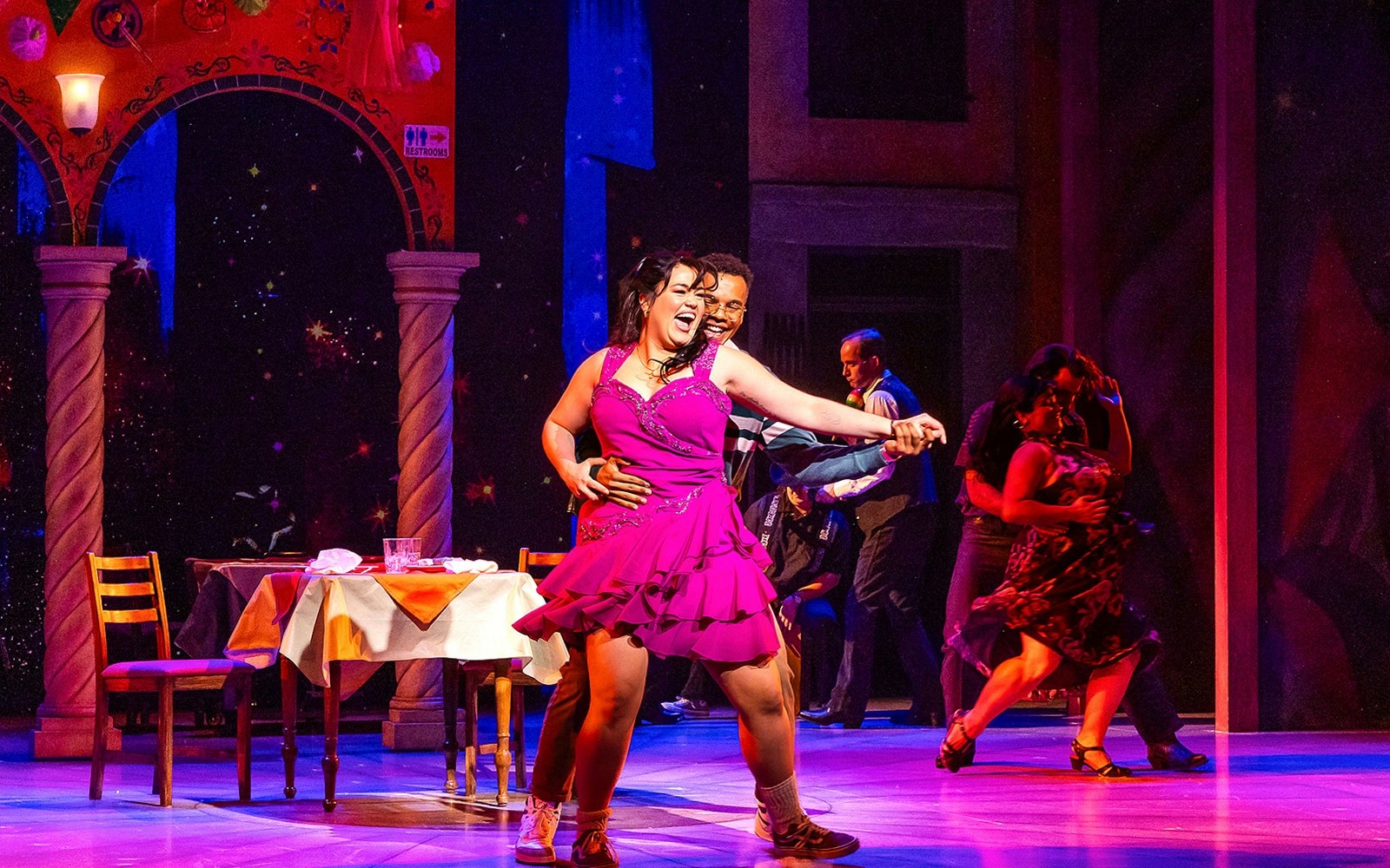Dancers performing in "Real Women Have Curves: The Musical" on a vibrant stage.