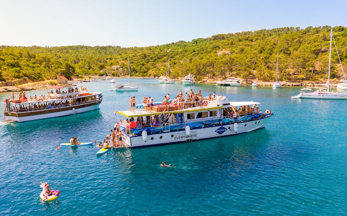 Tourists enjoying a boat cruise in the Blue Lagoon, Šolta, with surrounding yachts and lush greenery.