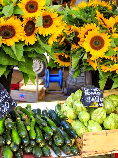 Sunflowers and fresh produce at a Provencal market stall.