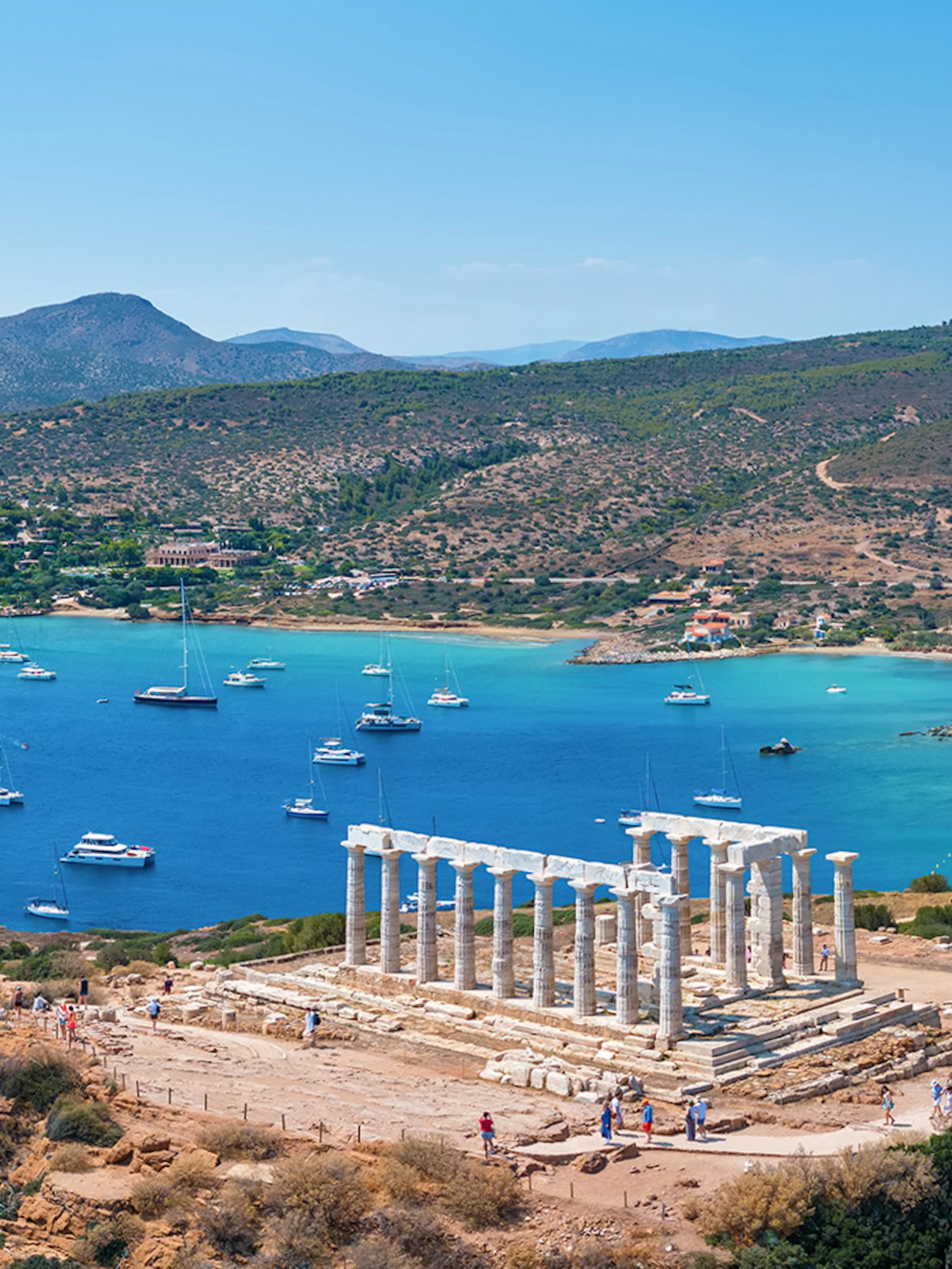 Panoramic view of the Temple of Poseidon at Cape Sounion with Aegean Sea and boats.