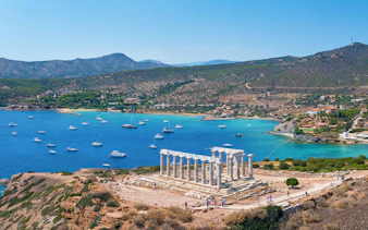 Panoramic view of the Temple of Poseidon at Cape Sounion with Aegean Sea and boats.