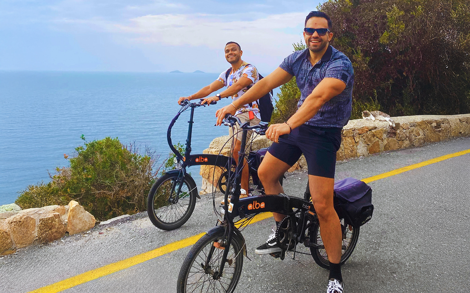 Two people riding e-bikes along a coastal road on Princes Island, Istanbul.