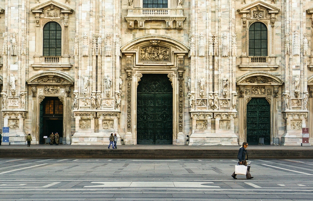 Main entrances of the Duomo in Milan with ornate architectural details.