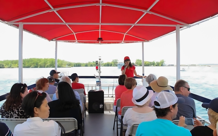 Tour guide speaking to passengers on a Toronto Harbour cruise boat.