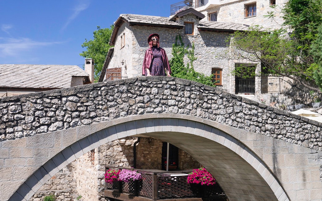 Kriva Cuprija bridge in Mostar with stone arch and historic buildings in the background.