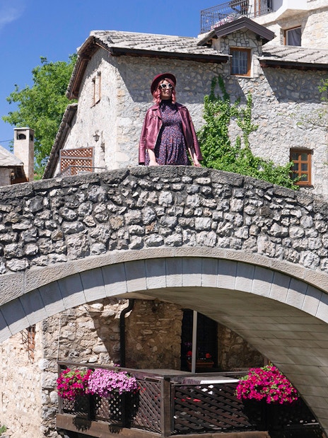 Kriva Cuprija bridge in Mostar with stone arch and historic buildings in the background.