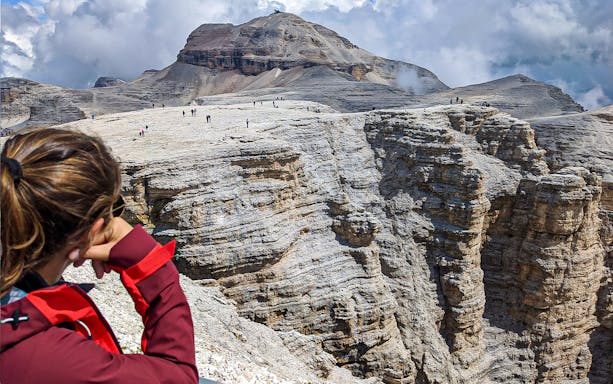 Guided tour group exploring rocky terrain of Dolomites Mountains from Lake Garda.