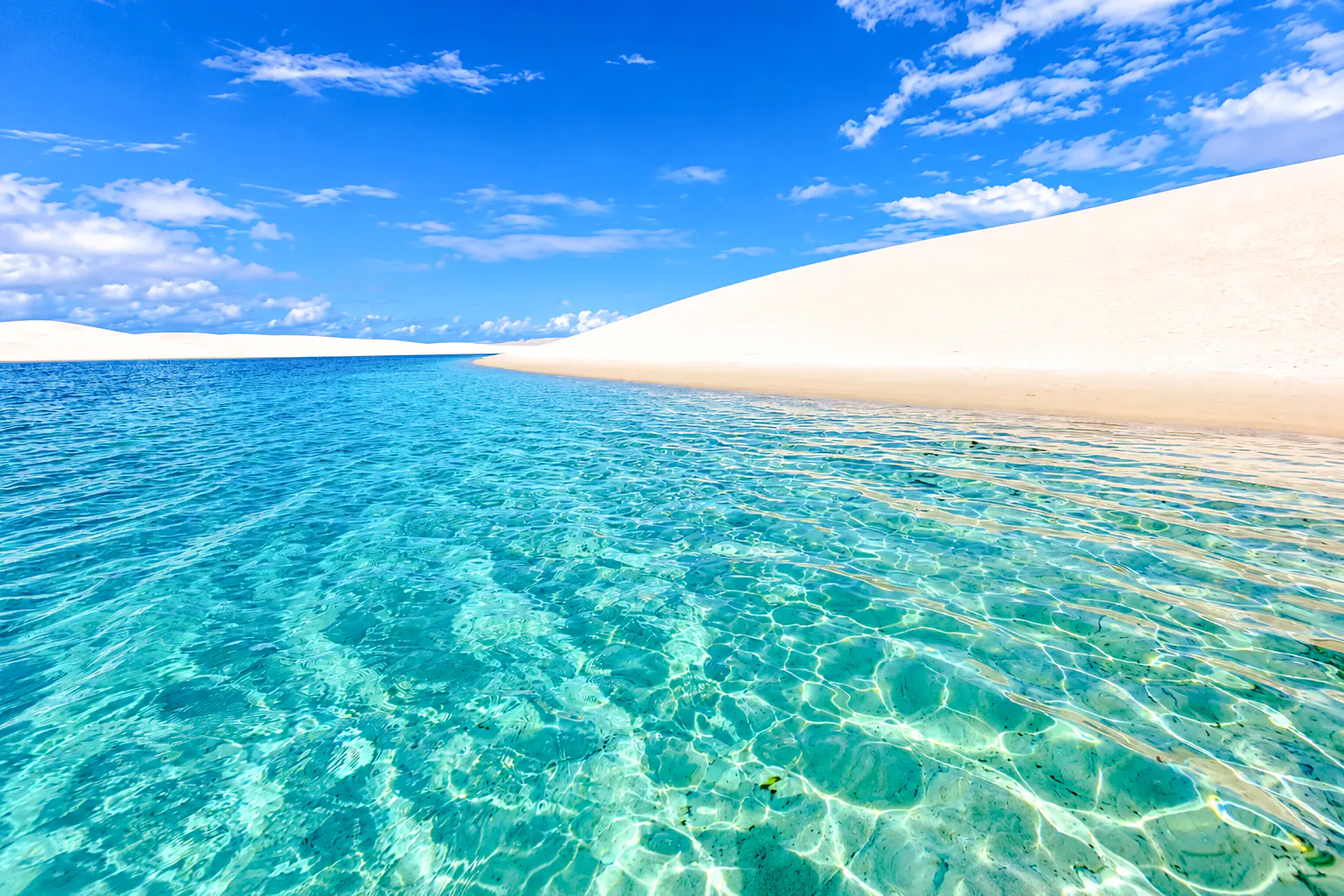 Clear lagoon with sand dunes at Lagoa Bonita, Barreirinhas, Brazil.