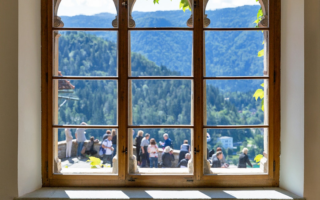 View from Bled Castle window overlooking mountains and visitors.