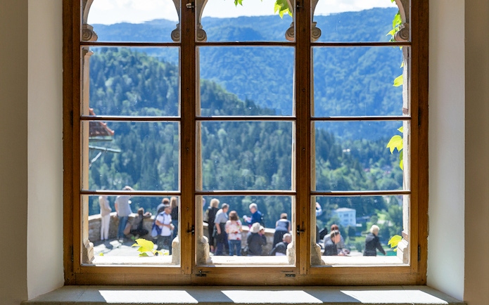 View from Bled Castle window overlooking mountains and visitors.