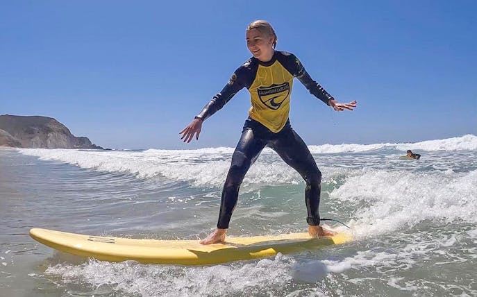 Surfer balancing on a board during a lesson at Carrapateira Beach.