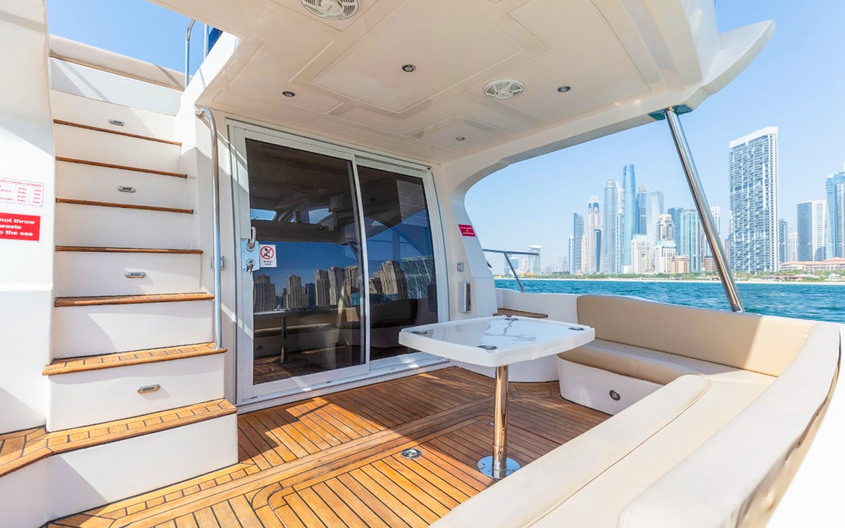 Private luxury yacht deck with Dubai skyline in the background.