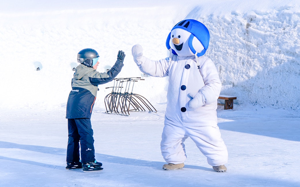 Child high-fiving snowman character at Snowman World, Santa Claus Village.