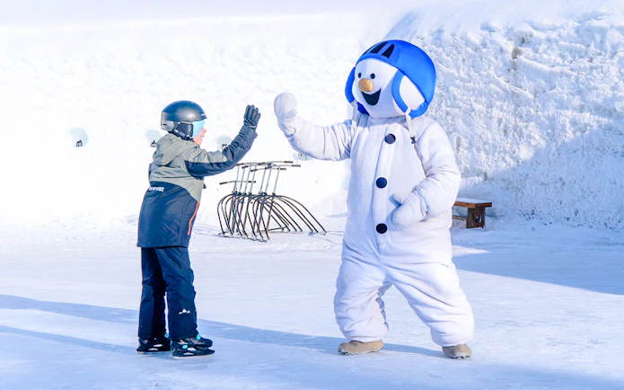Child high-fiving snowman character at Snowman World, Santa Claus Village.