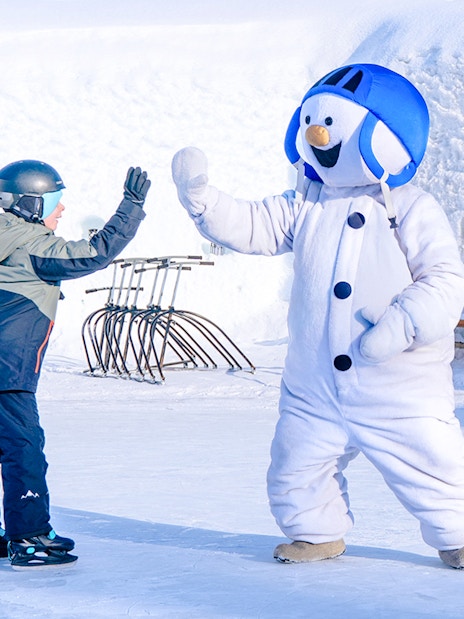 Child high-fiving snowman character at Snowman World, Santa Claus Village.