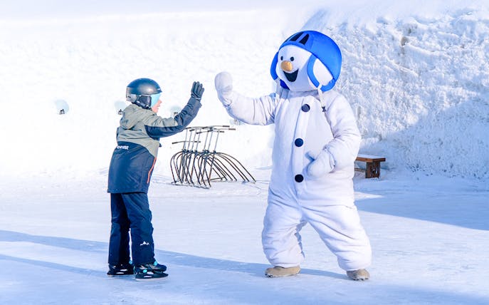 Child high-fiving snowman character at Snowman World, Santa Claus Village.