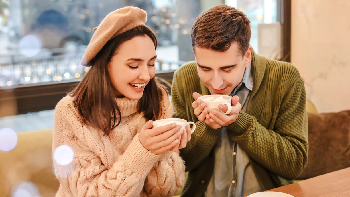 Couple enjoying hot chocolate in a cozy cafe during Christmas.