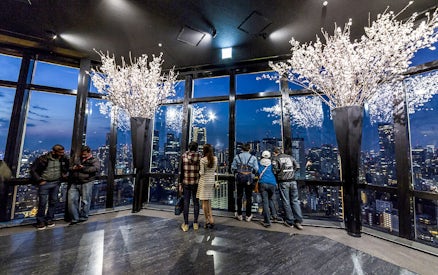 Tokyo Tower observation deck with visitors overlooking city skyline at night.