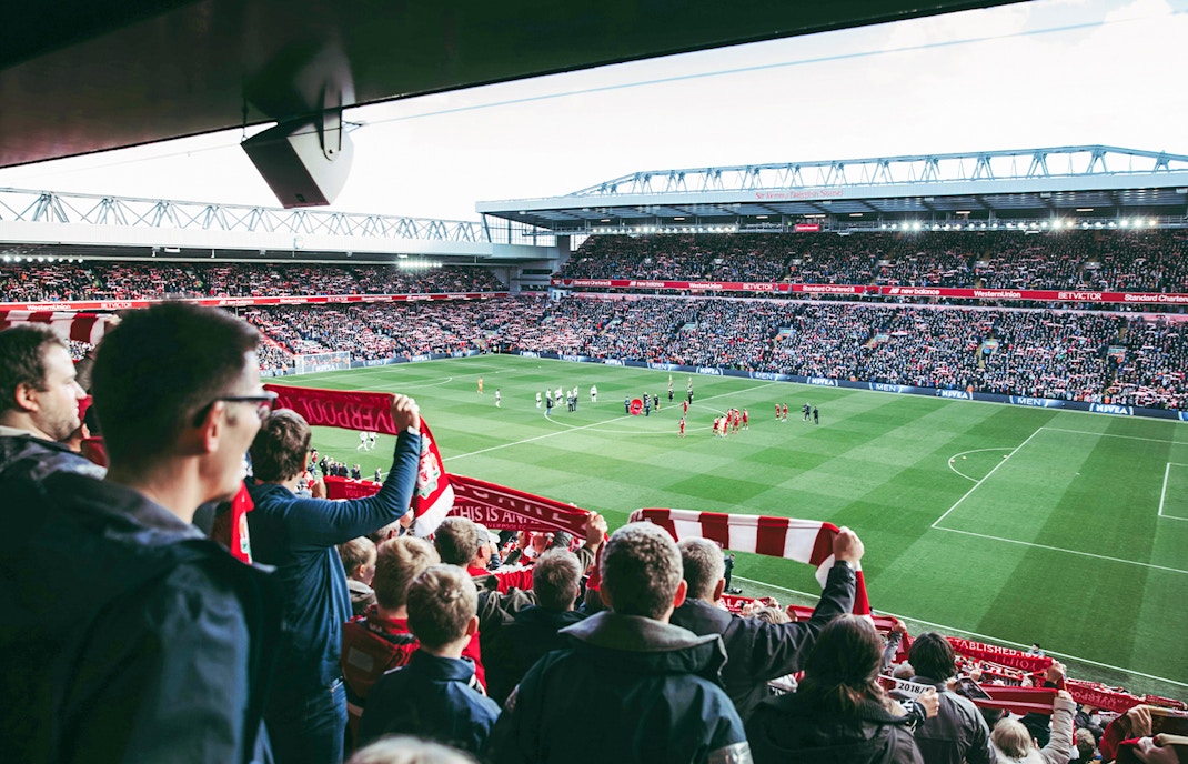 Fans watching a match at Liverpool FC's Anfield Stadium.