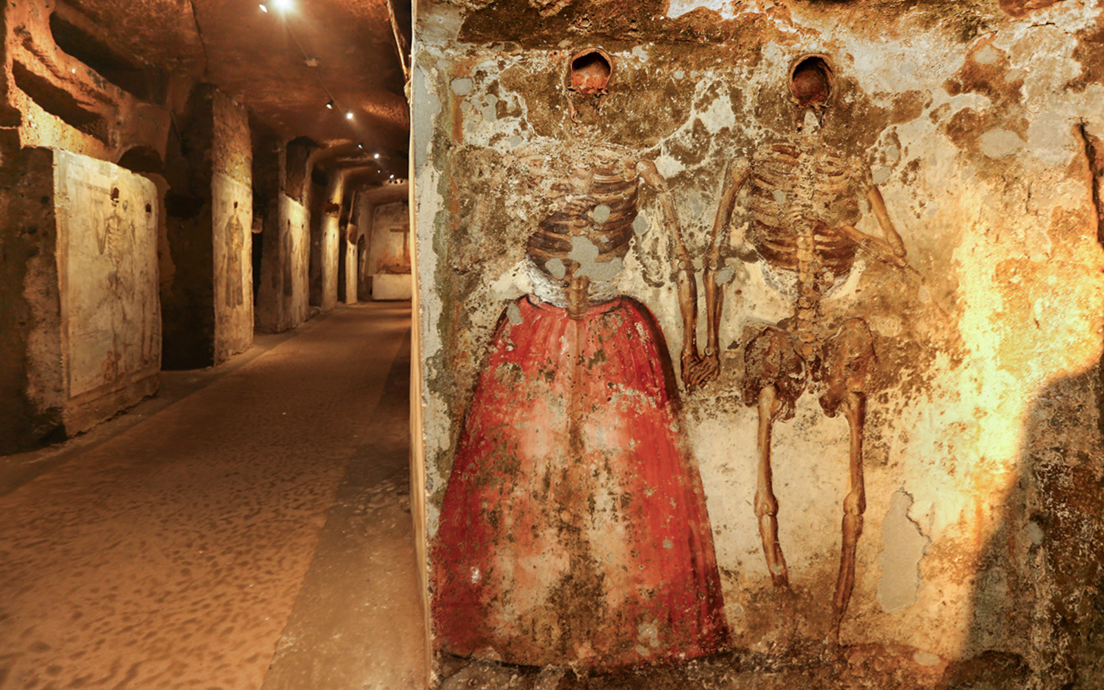 Skeletons in Catacombs of San Gaudioso, Naples, with painted clothing on walls.