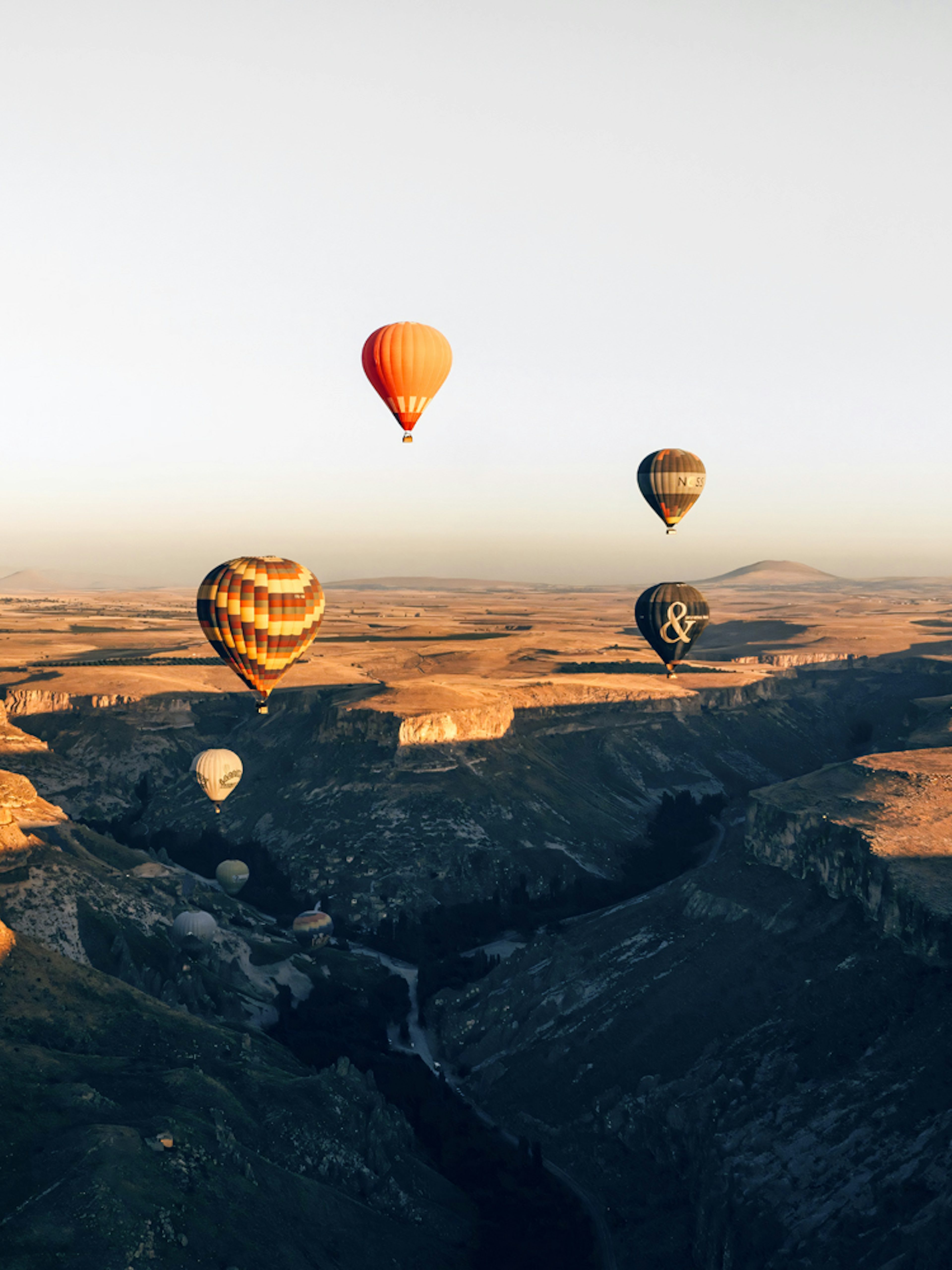 Hot air balloons floating over Soganli Valley, Cappadocia at sunrise.