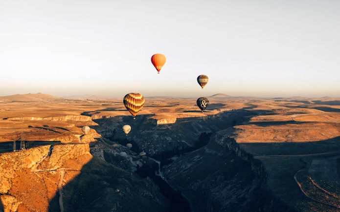 Hot air balloons floating over Soganli Valley, Cappadocia at sunrise.