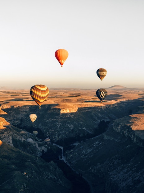 Hot air balloons floating over Soganli Valley, Cappadocia at sunrise.