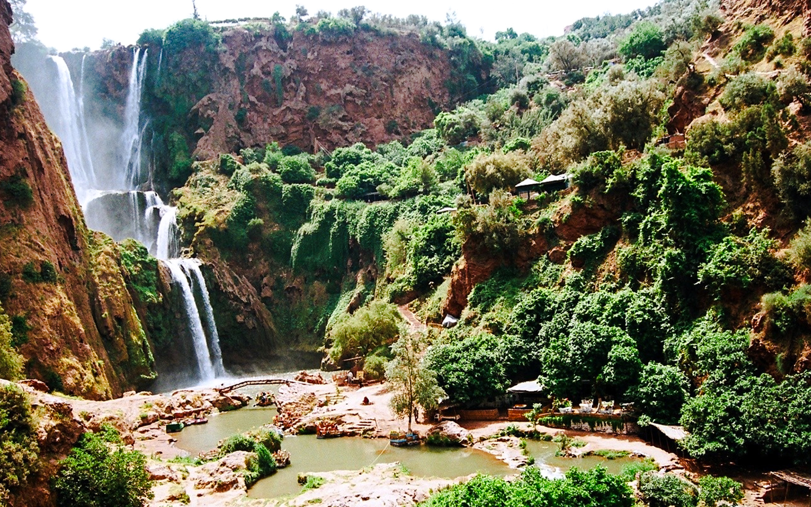 Ouzoud Waterfalls cascading down rocky cliffs surrounded by lush greenery in Morocco.