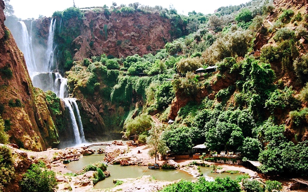 Ouzoud Waterfalls cascading down rocky cliffs surrounded by lush greenery in Morocco.