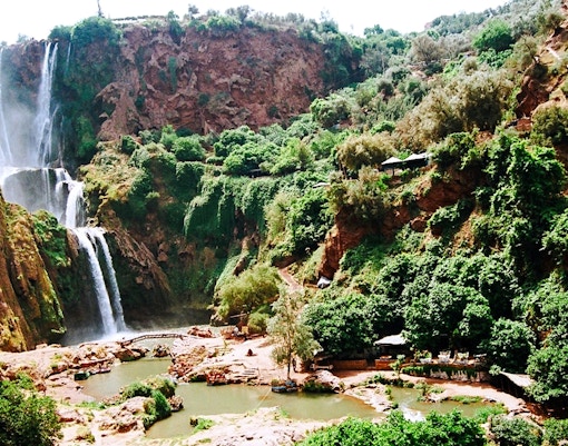 Ouzoud Waterfalls cascading down rocky cliffs surrounded by lush greenery in Morocco.