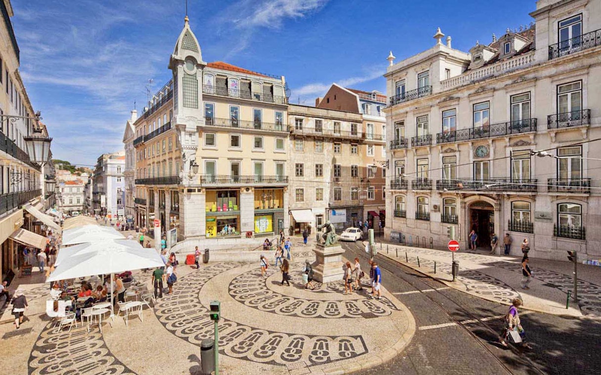 Lisbon city square with patterned pavement and historic buildings on a sunny day.