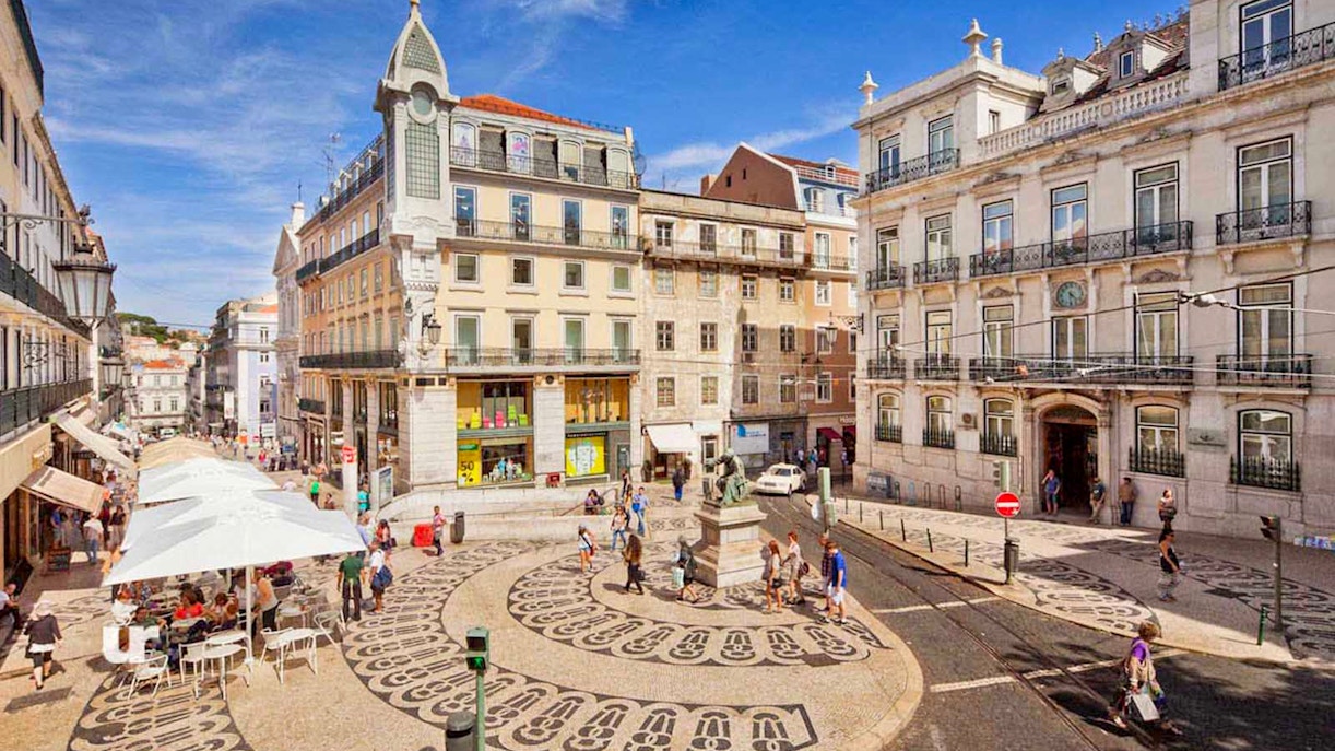 Lisbon city square with patterned pavement and historic buildings on a sunny day.