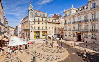 Lisbon city square with patterned pavement and historic buildings on a sunny day.