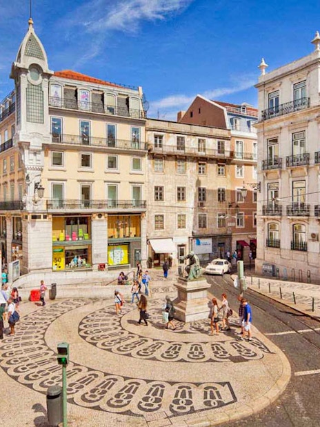 Lisbon city square with patterned pavement and historic buildings on a sunny day.