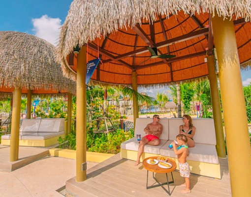 Family relaxing in a thatched cabana at Coral Cabana, Andamanda Phuket.