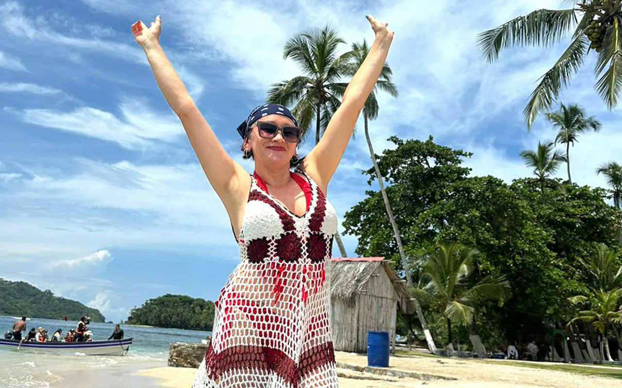 Tourist enjoying Isla Mamey beach with palm trees and boat, Panama City tour.