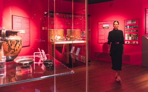 Exhibit of ancient artifacts at The Bridge Collection with visitor exploring displays.